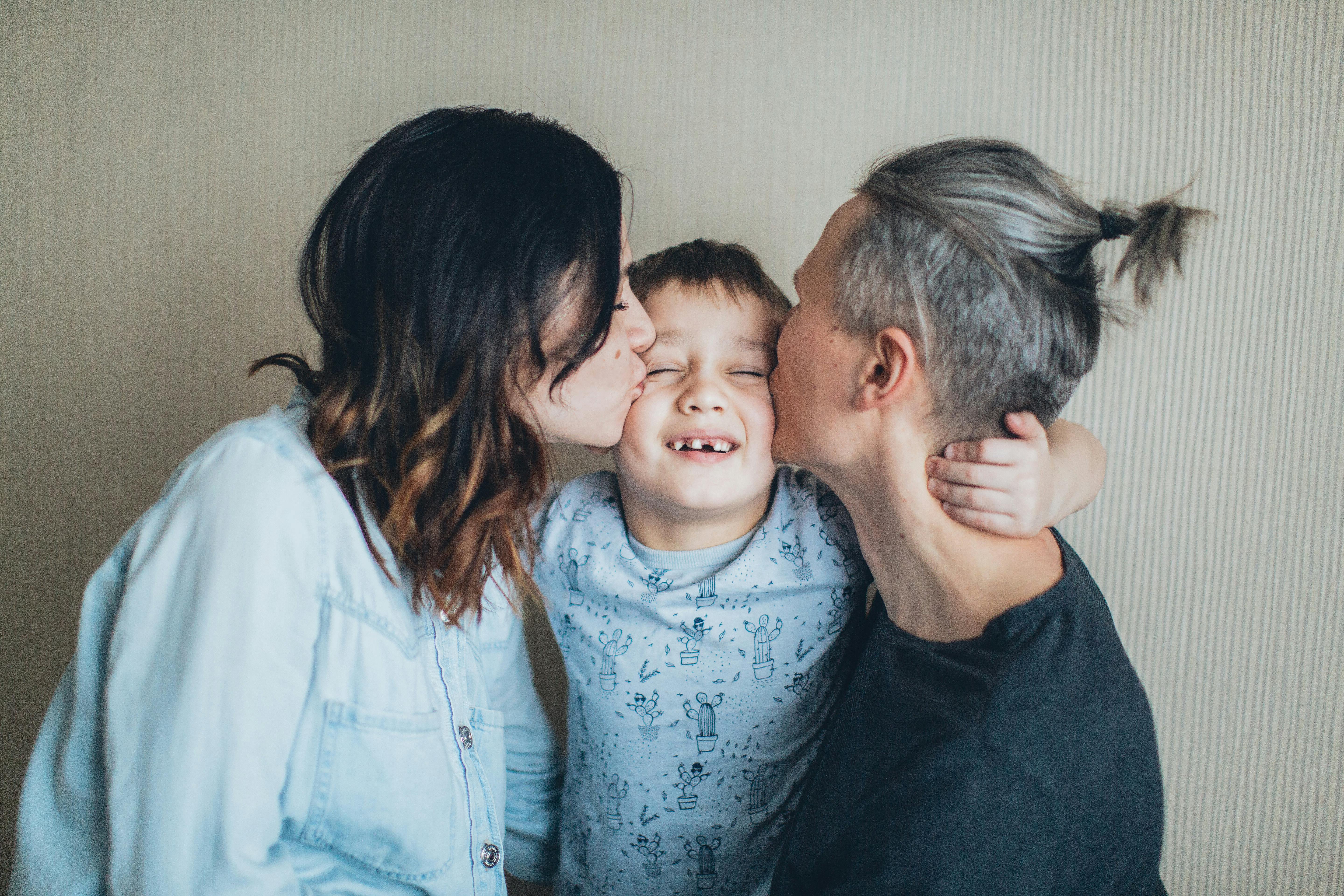 Parents affectionately kissing their young child