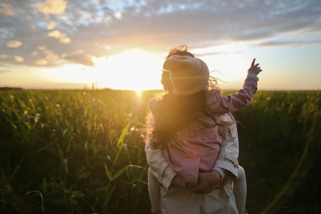 Mother carrying her young child through a field at sunset, symbolizing the protective love that drives families to get their life insurance decisions right