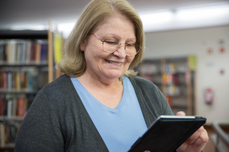 Smiling senior woman in her 60s browsing life insurance options on a tablet in Florida