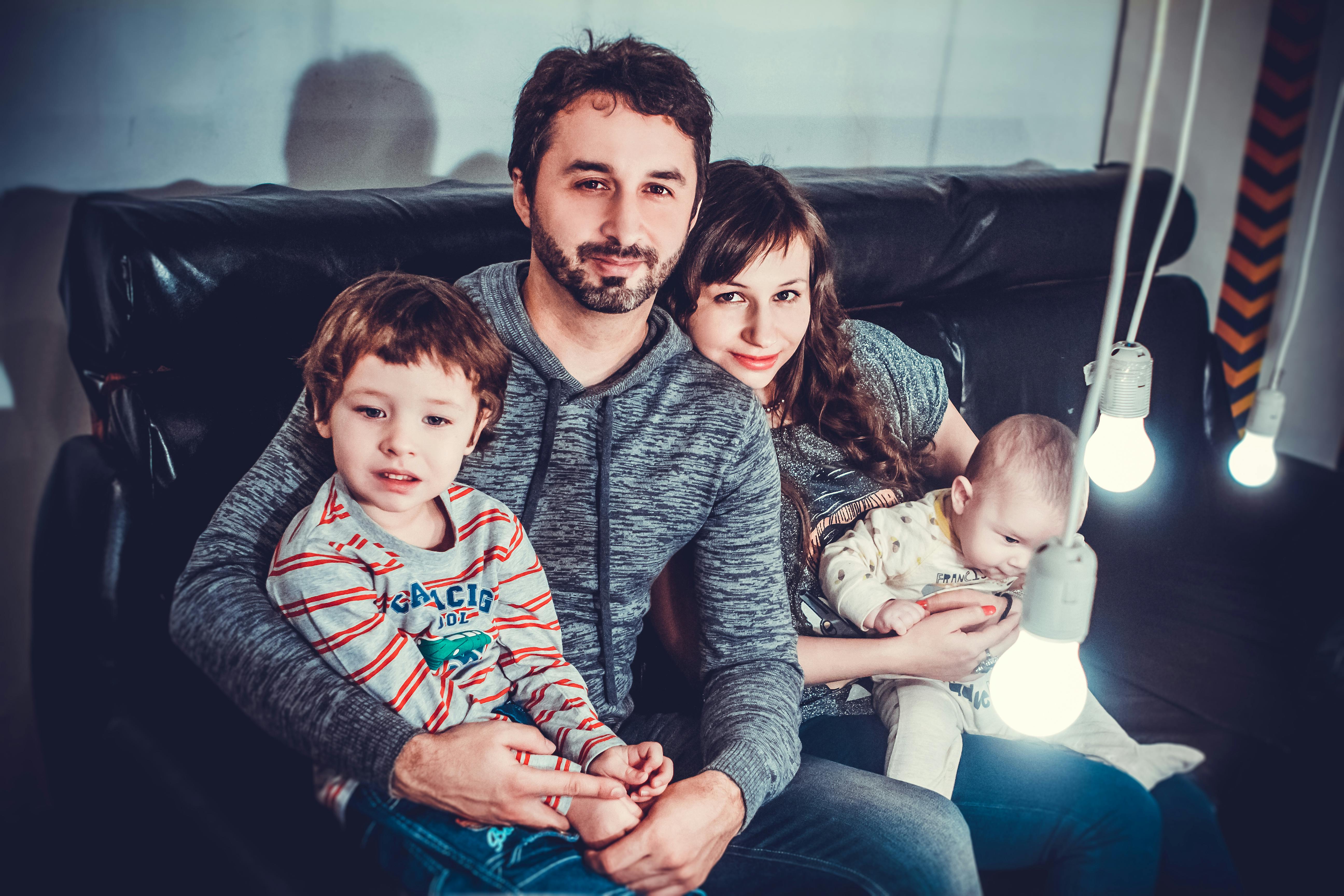 Family relaxing on couch together, representing the equal importance of both spouses in household life and the need for coordinated life insurance